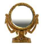 A Regency style giltwood and gesso circular mirror decorated with scrolls and putti, on a square