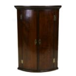 A George III mahogany bowfronted hanging corner cabinet, 68cms wide.