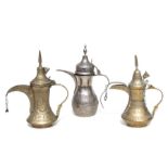 Two Turkish / Islamic brass dallah coffee pots, 30cms high; together with a white metal example (