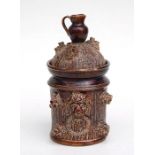 A treacle glaze tobacco jar and cover having a jug finial, 23cm high (A/F)