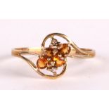 A 9ct gold dress ring set with four orange stones and two small diamonds, approx UK size 'O', 1g.