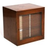 An early 20th century oak microscope slide cabinet with single glazed door enclosing twenty eight