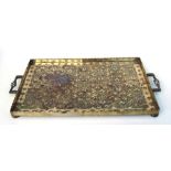 An Arts & Crafts style brass rectangular two-handled tray with embossed decoration, 65cms wide.