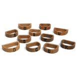 Eleven 'D' shaped oak napkin rings, probably Heals, each with inset wood darker initial.