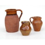 An earthenware studio pottery jug, 18cm high and two others similar (3)