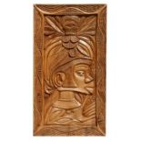 A carved wooden panel depicting an Asian figure wearing a headdress, 43 by 76cms.