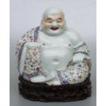 A Chinese famille rose seated Buddha on hardwood stand, impressed seal mark to the underside,