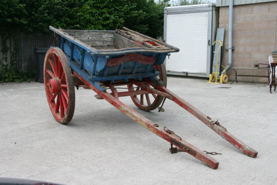 A traditional horse drawn tipping cart with wooden shafts, steel and wooden cartwheels and bears