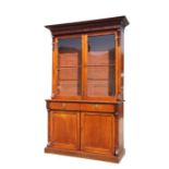 An early 19th century mahogany bookcase on cupboard, the pair of glazed doors enclosing a shelved