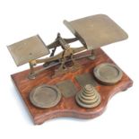 A large set of oak and brass postal scales with graduated brass weights, 37cms wide.