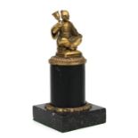 A gilt bronze figure depicting an Asian gentleman seated cross legged on a cushion ringing a bell,