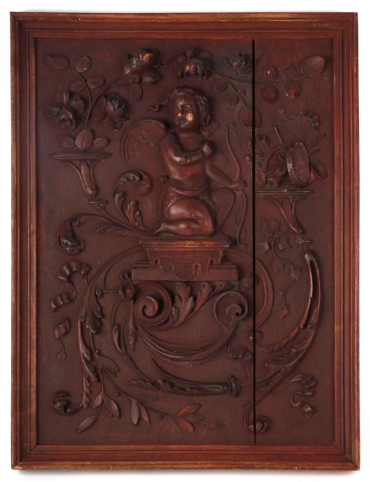 A 19th century carved wooden panel depicting a cherub and scrolling flowering foliage, framed, 26 by