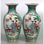 A pair of Chinese famille rose vases decorated with figures within panels on a turquoise ground, red
