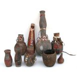 A collection of African Tribal gourd water carriers, some with bead decoration and wooden cup