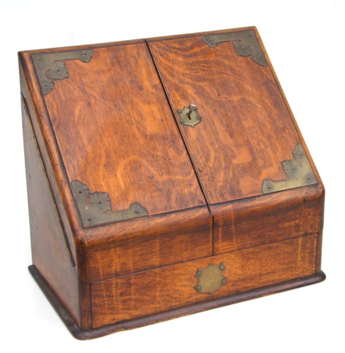 A Victorian brass mounted oak stationery box with hinged sloped front enclosing a fitted interior