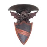 A carved wooden wall bracket in the form of a winged griffin above a shield, 42cms high.