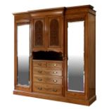 A large Edwardian oak breakfront wardrobe with dentil cornice above a central section with two