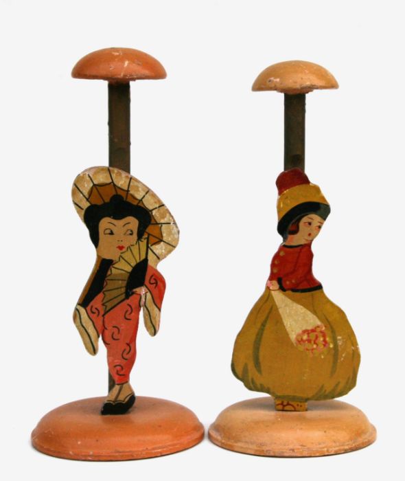 A pair of early 20th century painted wooden hat stands depicting two girls, 24cms high (2).