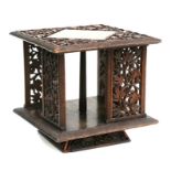 A carved hardwood table top revolving bookcase, pierced and carved with foliage and berries, 30cms
