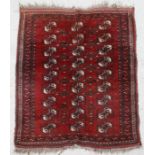 A Persian woollen Turkoman rug with repeating rows of guls within borders, on a red ground.