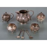 An Indian silver four-piece cruet set with three spoons, finely chased with village scenes; together