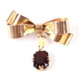 A Murle Bennett & Co 15ct gold ribbon bow brooch with red stone (possibly garnet) pendant drop, 3cms