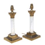 A pair of gilt metal and white marble column table lamps with ornate capitals, 32cms high.