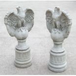 A large pair of stoneware garden eagles perched on a sphere with their wings outswept, 97cms high (