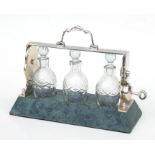 A silver plate and marble three-bottle miniature tantalus, 26cms wide.