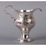 A George III silver cream jug with embossed decoration depicting a cottage and a bird, initialled,