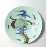 A Chinese enamelled plate decorated with a dragon chasing a flaming pearl on a celadon glaze, blue