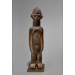 A Lobi standing female figure, Burkina Faso with a centrally ridged head and well defined features,