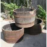 Three metal bound half barrel planters, 65cms diameter (a/f) (3).