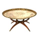 A large Middle Eastern brass tray-top coffee table on a folding hardwood stand, 93cms diameter.