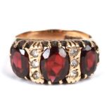 A 9ct gold dress ring set with three garnets and six white stones, approx UK size 'L', 4.6g.