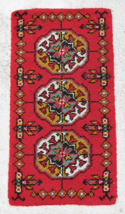 A rug with repeating guls on a red ground, 140 by 70cms.