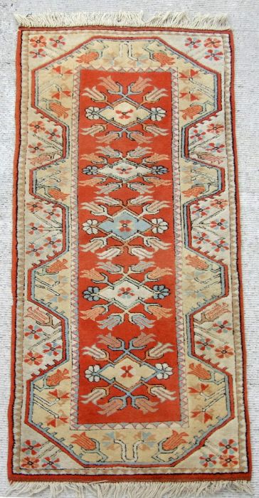 A Persian hand knotted woollen runner with stylised tulip design within geometric borders, on a