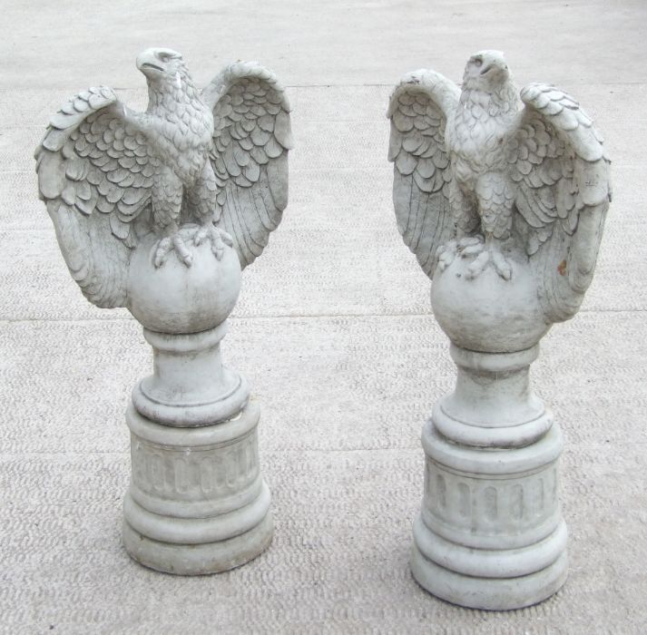 A large pair of stoneware garden eagles perched on a sphere with their wings outswept, 97cms high (