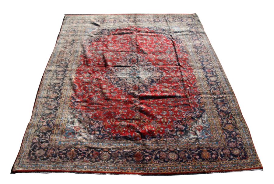 A Persian Kashan woollen hand knotted carpet with foliate design on a red ground, 408 by 310cms (