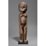 A Lobi standing male figure, Burkina Faso with a small hair knot to the back of the head and with