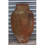A terracotta olive jar of tapering cylindrical form with banded decoration, 67cms high.
