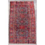 A Persian Azari hand knotted woollen rug with geometric design on a red ground, 290 by 155cms (