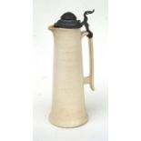A large early 20th century cream glazed Bretby jug with associated pewter cover, 37cms high.