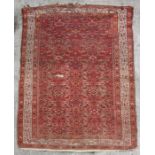 A Persian rug with repeating medallions within a foliate border, on a red ground, 98 by 148cms.