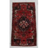 A Persian rug with central medallion on a red ground within a multi border, 230 by 104cms.