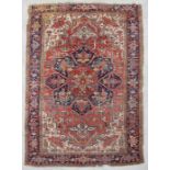 A Persian Heriz rug with large central floral medallion within geometric floral borders, on a red