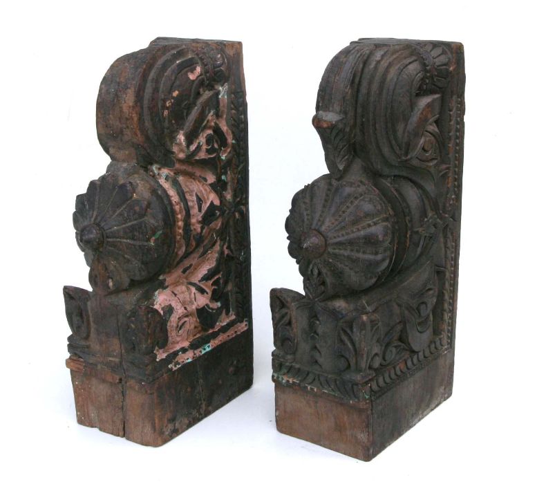 A pair of Indian carved hardwood temple corbels with remnants of paint, 47cms high (2).