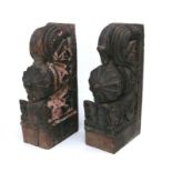 A pair of Indian carved hardwood temple corbels with remnants of paint, 47cms high (2).