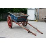 A traditional horse drawn tipping cart with wooden shafts, steel and wooden cartwheels and bears