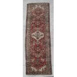 A Persian runner with central gul and repeating motifs on a red ground within a multi border, 310 by